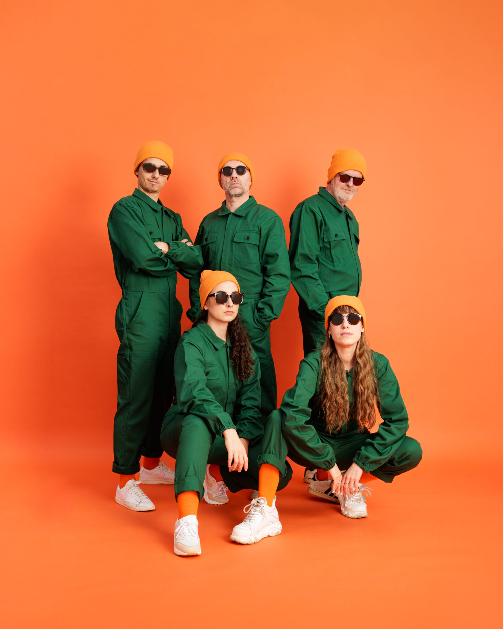 équipe d'Oioo Studio, photographe professionnel à Nantes. 5 personnes en salopettes vertes sur fond orange